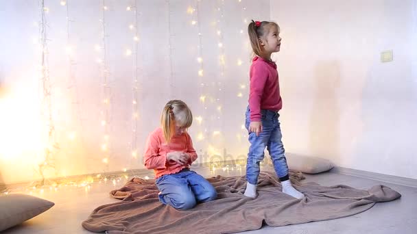 Дві маленькі дівчата сидять на підлозі і грають . — стокове відео
