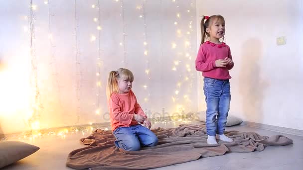 Zwei kleine Schwestern im weihnachtlich dekorierten Zimmer. — Stockvideo