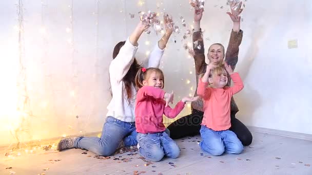 Dos madres jóvenes sentadas con hijas pequeñas en el suelo y posando en la videocámara . — Vídeos de Stock