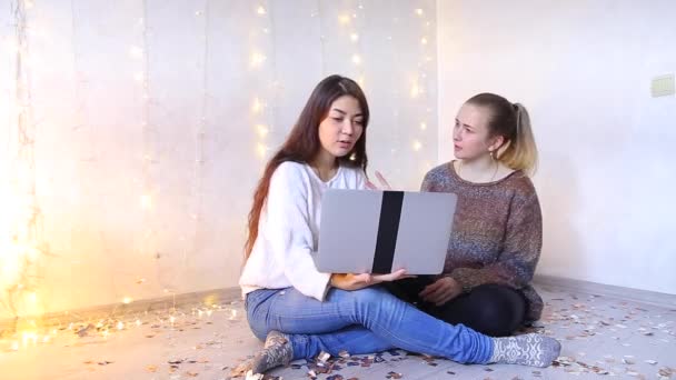 Két gyönyörű lányok emeleti nappaliban ül, és válassza a termékek online áruház.