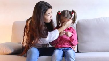 Küçük kızı oturma odasında kanepede oturan genç anne.
