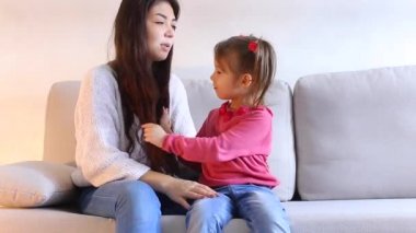 Güzel genç anne ile küçük kızı kanepe, kadın saç ile oynayan Bebek bakimi