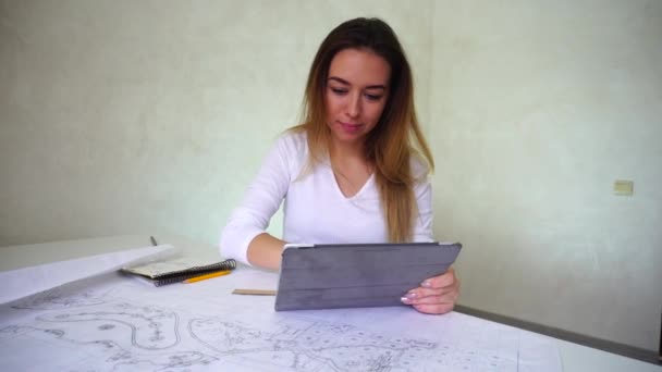 Студент-инженер, работающий над проектом дома, улыбающаяся молодая женщина делает домашнее задание с помощью планшета — стоковое видео