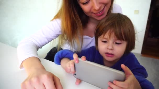 Madre enseñando a su hija a leer usando la aplicación en el teléfono inteligente . — Vídeo de stock