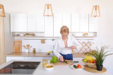 Mutfak kız smartphone elinde tutan ve sebze fotoğrafı çeker