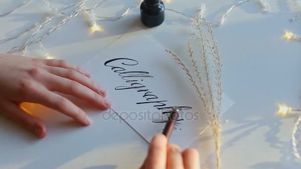 Рисует каллиграфию на белой бумаге перьевой ручкой . — стоковое видео
