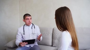 Kız kim tedavi reçete Doktor geldi. Adam ve kadın tıbbi ofis üzerinde oturan gri duvar arka plan kanepe.