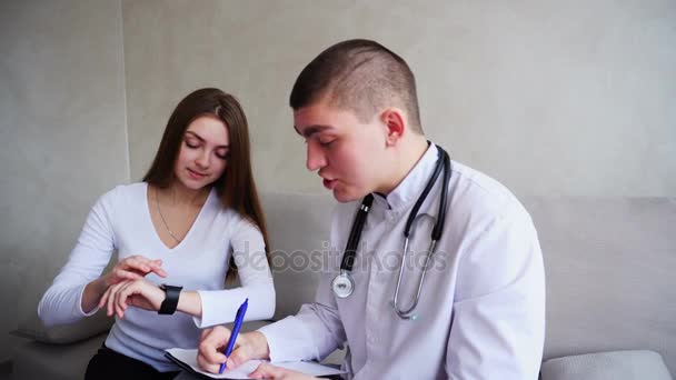 Il dottore mostra funzioni mediche pazienti femminili di orologio intelligente, usi nuove tecnologie in ufficio di ospedale . — Video Stock