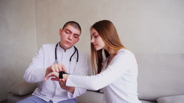 Portretten van de arts verklaart patiënt hoe te gebruiken smart Watch wilt controleren van hun gezondheid en zitten op de Bank in ziekenhuizen kantoor. — Stockvideo