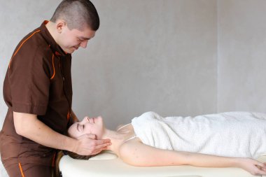 Adam masör güçlü elleriyle yalan genç kız, boyun kneads