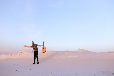 Arap adam çöl güzelliği ile ilham gider ve gitar çi çalış