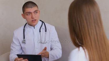 Olgun kadın kim dinler ve yazıyor doktor görmeye geldim. Adam ve tıbbi ofis gri duvar arka plan üzerinde kanepede oturan kadın.