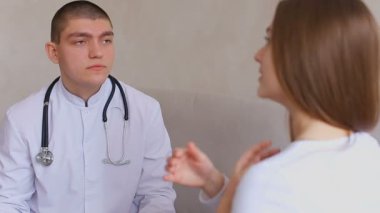 Genç kız tedavi reçete için doktor geldi. Adam ve kadın tıbbi ofis üzerinde oturan gri duvar arka plan kanepe.