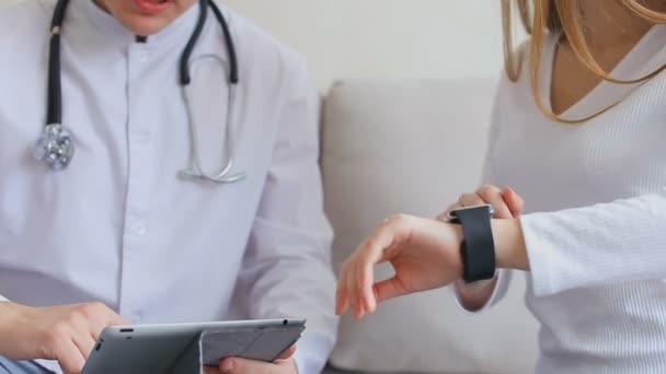 Технологічна медицина докторат і пацієнтка-жінка вивчають медичні функції розумних годинників і планшетів, використовують нові технології в офісі лікарні . — стокове відео