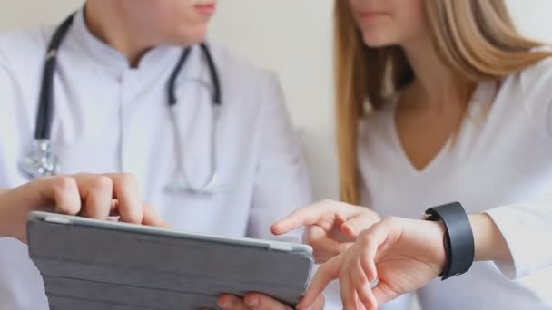Medicina médico e feminino paciente estudo funções médicas de smart Watch e tablet, usar novas tecnologias no escritório do hospital . — Vídeo de Stock