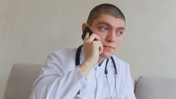 Guter Arzt am Handy berät Patienten, die im Büro des Krankenhauses auf der Couch sitzen. — Stockvideo