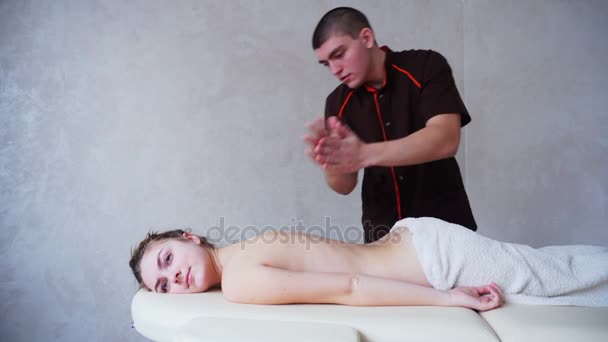 Masajista desinfecta las manos y habla con el cliente femenino, que yace en el sofá en el consultorio médico . — Vídeo de stock