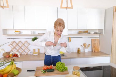 Mutfak kız smartphone elinde tutan ve sebze fotoğrafı çeker