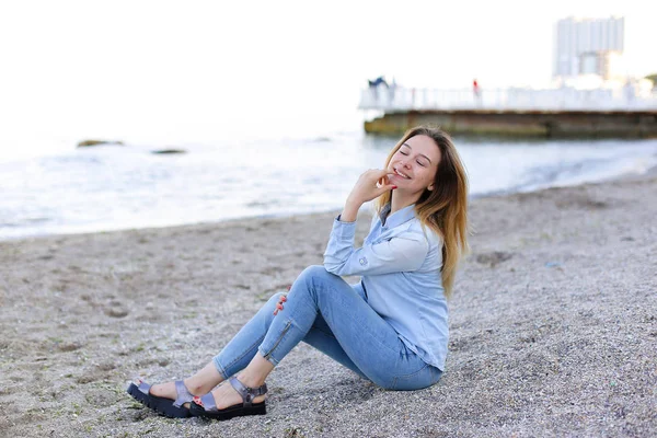 Sonriente joven descansa en la playa y posa en la cámara, sentado —  Fotos de Stock