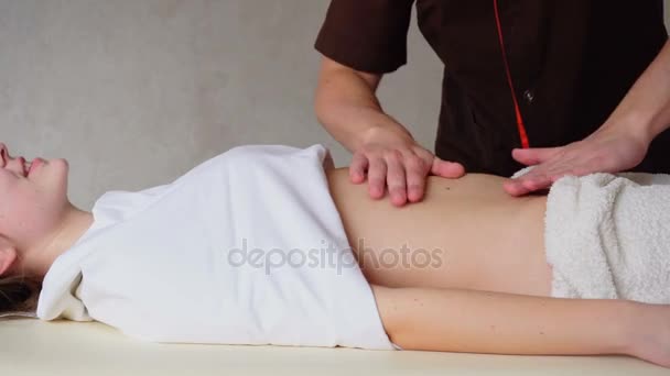 Masajista masculino fuerte con movimientos suaves de la mano amasa el vientre de la mujer clientes, que se encuentra en la sala de cosmetología . — Vídeo de stock