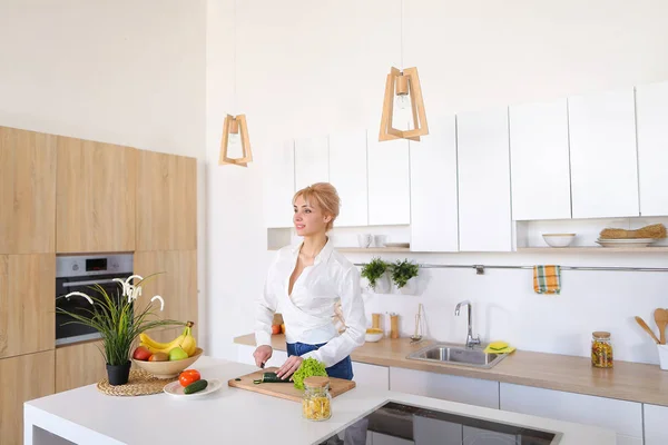 Atractiva ama de casa femenina corta pepino con cuchillo y sonrisas , — Foto de Stock