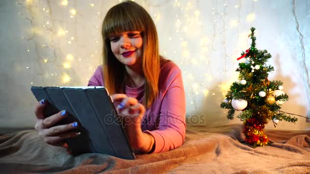 Jocund chica jugando con la tableta en la leva . — Vídeos de Stock