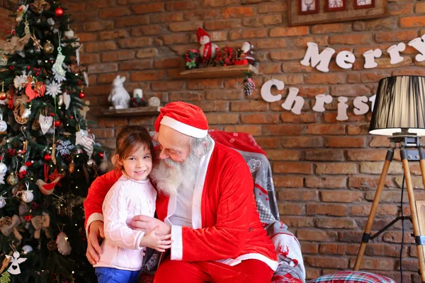 Strong embrace between happy female child of girl and Santa Cla