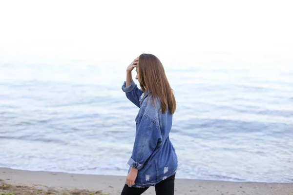 Stylish woman steps confidently along seashore and poses in came — Stock Photo, Image