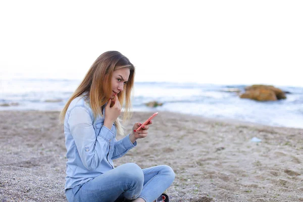 Hermosa chica charla por teléfono con sonrisa y se sienta en la playa n — Foto de Stock