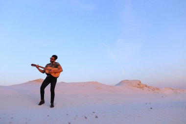 Arap adam çöl güzelliği ile ilham gider ve gitar çi çalış