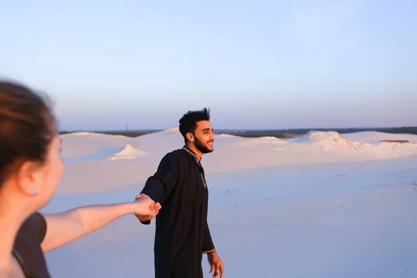 Jonge mannelijke moslim meisje met de hand leidt en wandelingen langs de woestijn bij s — Stockfoto