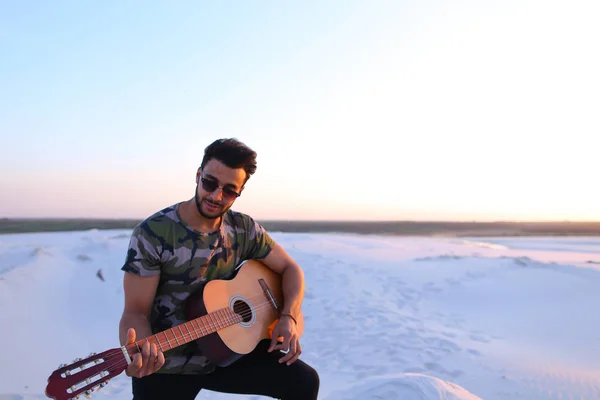 Ritratto di giovane musulmano che suona la musica alla chitarra tra san — Foto Stock