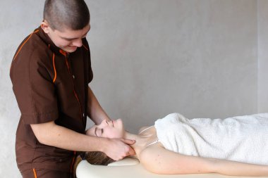 Adam masör güçlü elleriyle yalan genç kız, boyun kneads