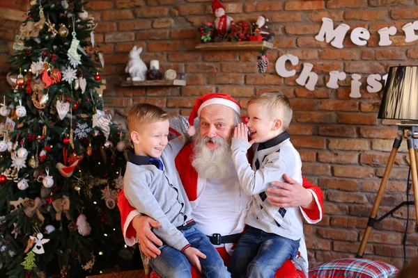 Dois meninos gêmeos alternadamente fazer desejo na orelha de Papai Noel em de — Fotografia de Stock