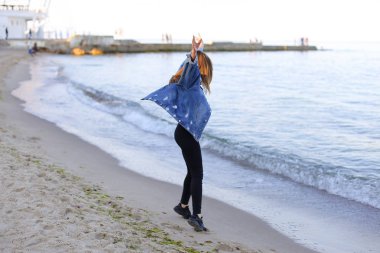 Çekici kız sahil boyunca yürür ve neşeyle kum üzerinde aptallar