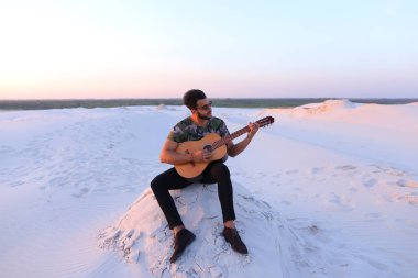 Sevimli genç erkek Arap ses gitar, Hill'de oturan sahiptir