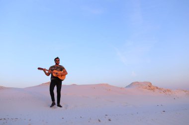 Arap adam çöl güzelliği ile ilham gider ve gitar çi çalış
