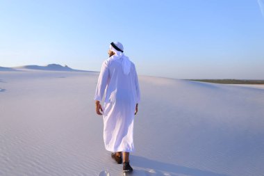 Neşeli Müslüman erkek c yüzünde gülümseme ile çöl üstünde yürür