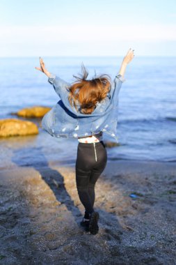 Çekici kız sahil boyunca yürür ve neşeyle kum üzerinde aptallar