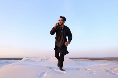 Neşeli Arap adam telefonla iletişim kurar ve m satırda sekerek