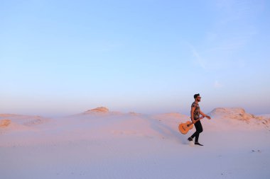 Dese aracılığıyla elinde gitar ile görkemli Müslüman genç adam yürüyor