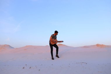Arap adam çöl güzelliği ile ilham gider ve gitar çi çalış