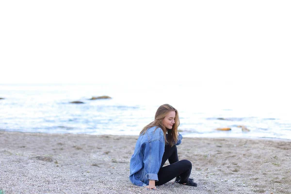 Leende ung kvinna vilar på stranden och poserar i kameran, sitter — Stockfoto