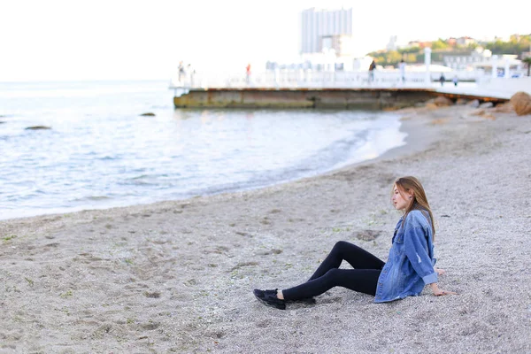 Güzel ve genç birbayan sahilde oturan rahatlatır ve görünümü o sahiptir — Stok fotoğraf