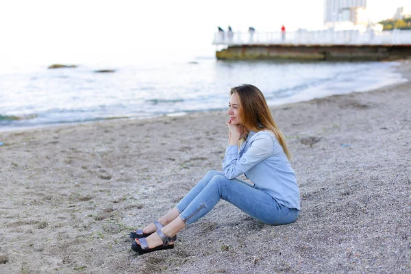 Sonriente joven descansa en la playa y posa en la cámara, sentado —  Fotos de Stock