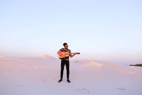 Gutaussehender arabischer Mann, der mitten auf dem Boden stehend Gitarre spielt — Stockfoto