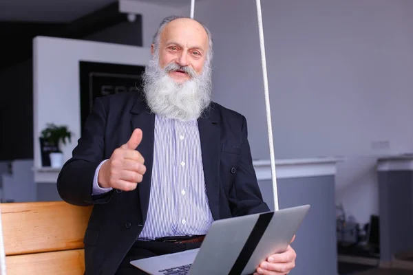 Oude gepensioneerde man maakt gebruik van de laptop en communiceert met collega's beh — Stockfoto