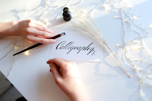 Lány ír toll szökőkút kalligrafikus betűkkel, asztalnál ülő — Stock Fotó