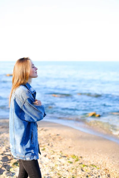 Pretty woman smiles easily and looks at horizon, standing on sho Stock Photo