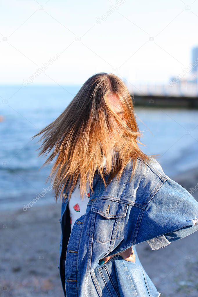 Happy young female develops hair and poses on camera, standing o
